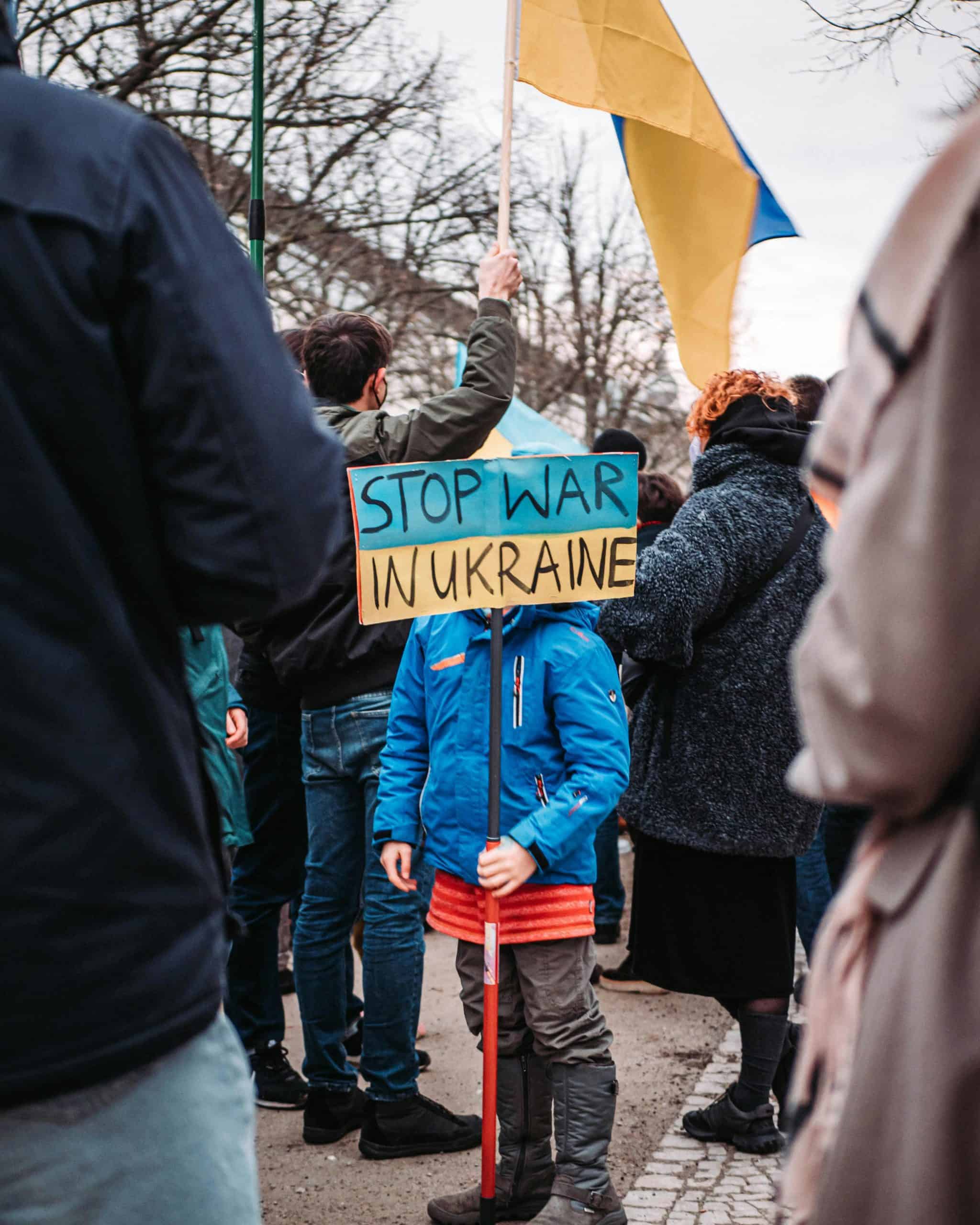 A child holds a 'Stop War in Ukraine' sign during a peaceful protest outdoors in Berlin, Germany.