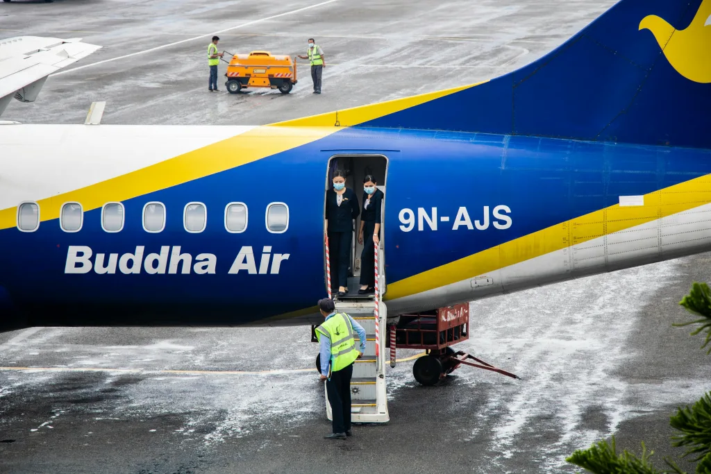 Buddha air Buddha Airplane with crew members standing at Pokhara Airport entrance, Nepal where buddha air's missing tire was found.