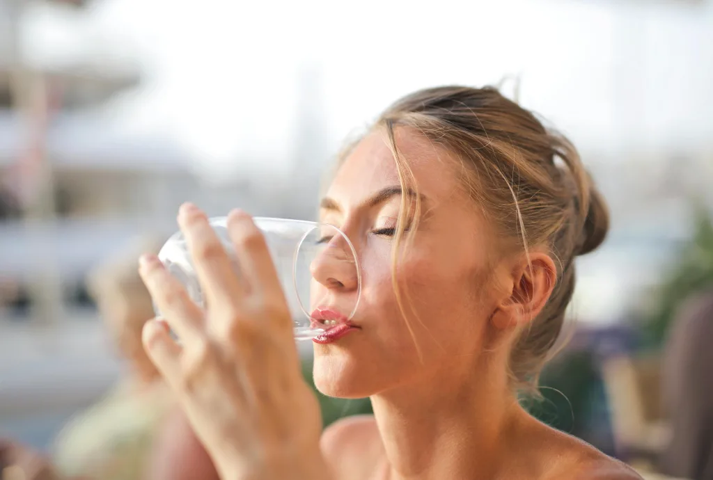 drink water Close-up of a woman drinking water with a serene expression outdoors.