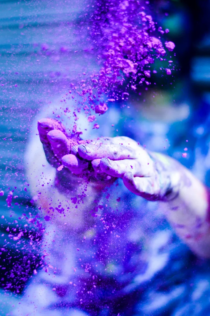 holi Close-up of hands tossing vibrant purple powder during Holi festival celebration.
