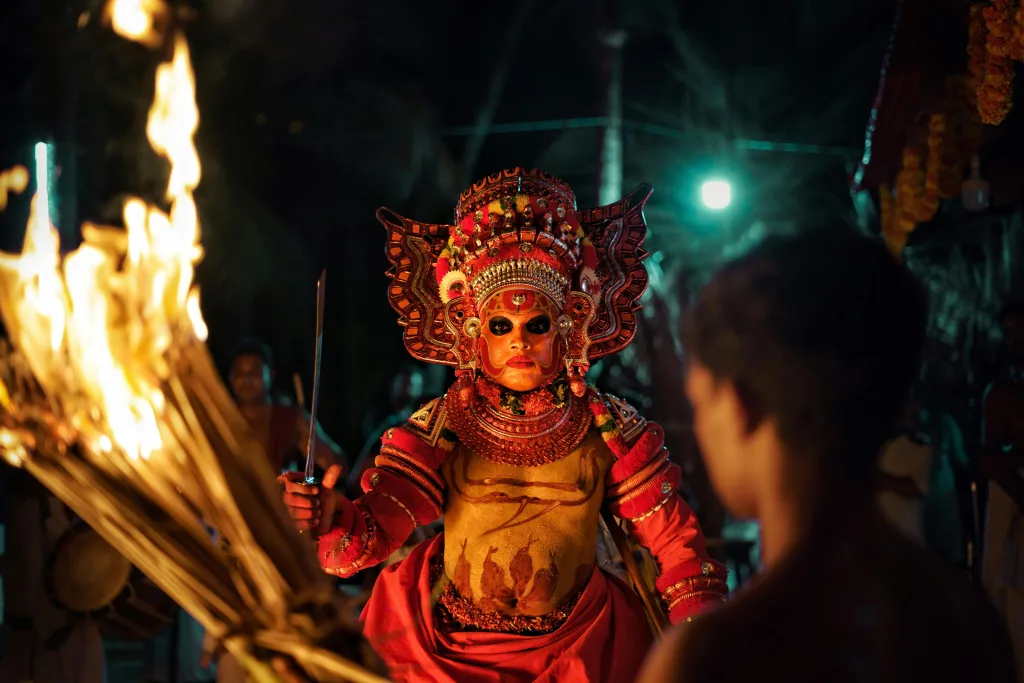 pexels-photo-3285746-3285746 Captivating image of a traditional Theyyam performer with fire in a night festival setting.