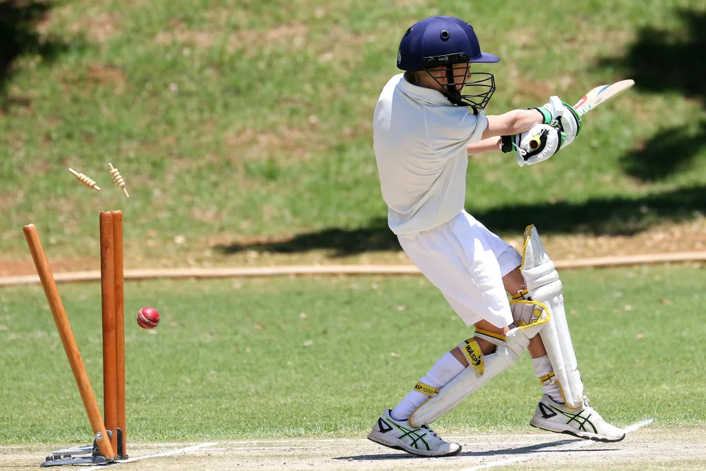 pexels-photo-3602833-3602833 Young cricket player in full gear performing a sweep shot on a sunny day outdoors.