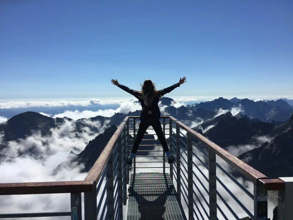 success A woman stands on a viewing platform in Vysoké Tatry, Slovakia, surrounded by clouds and mountains, embracing freedom.