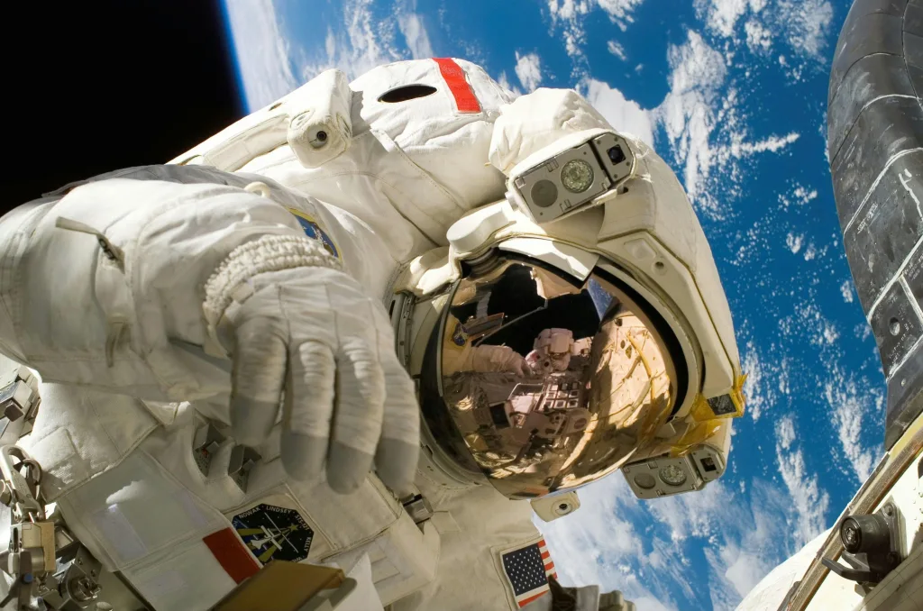 sky-earth-space-working Astronaut floating in space during a spacewalk, visible Earth in the background.