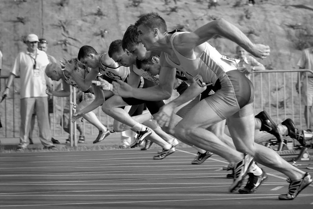 spot-runs-start-la-34514 Athletes burst from the blocks during a sprint race, captured in monochrome.