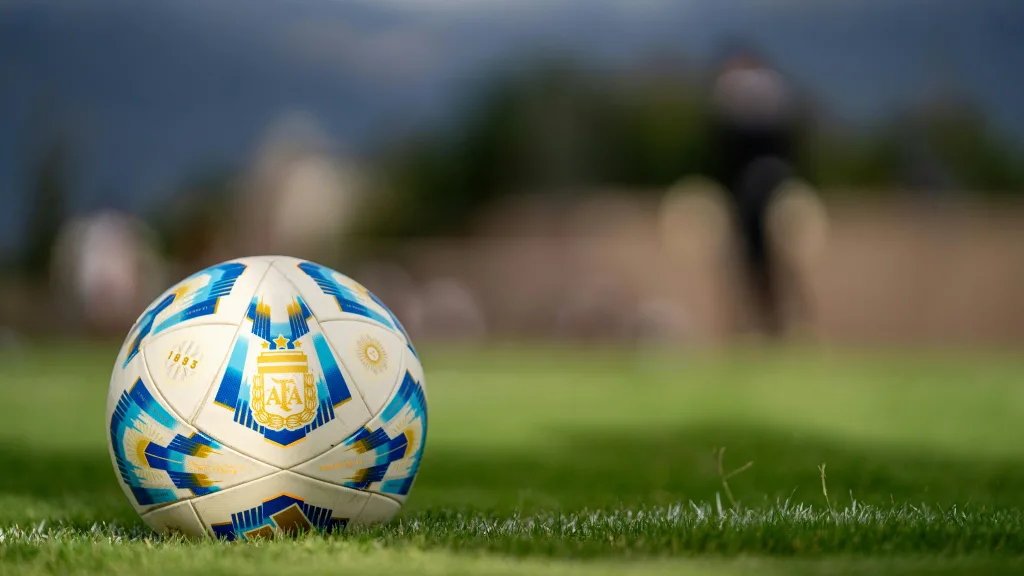 pexels-photo-30986212-30986212 Close-up of an official Argentine soccer ball resting on a green field with a blurred background.