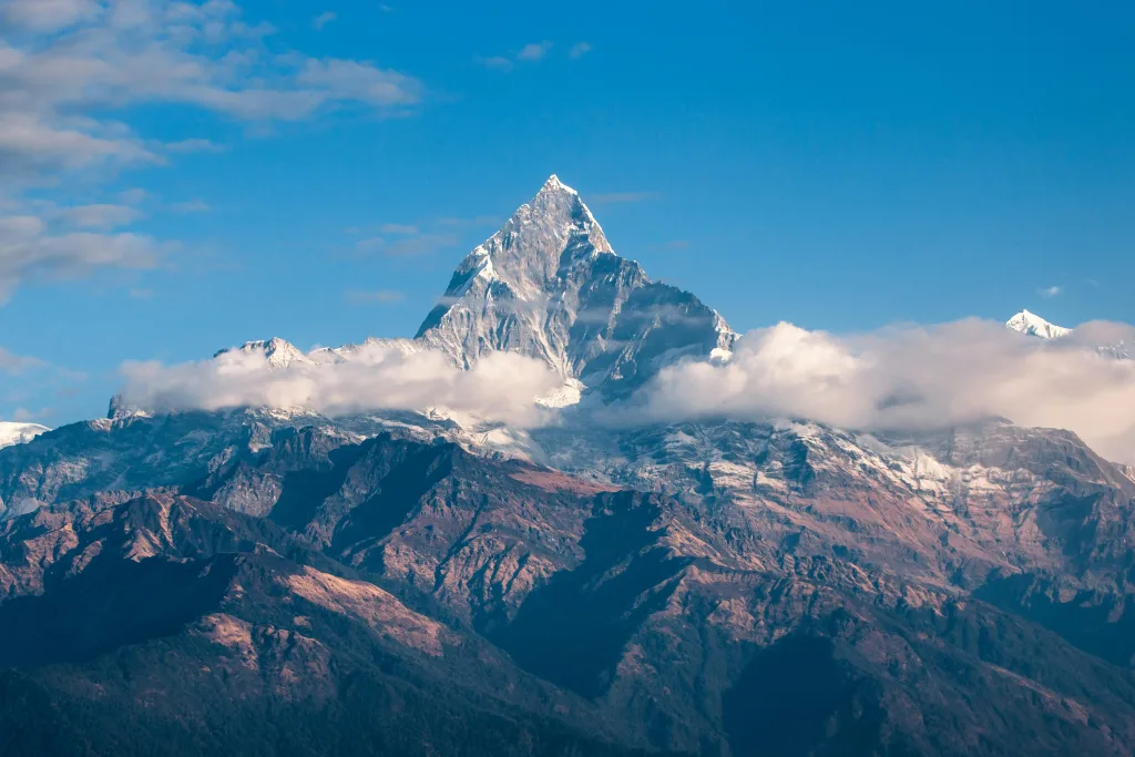 pexels-photo-417173-417173 Breathtaking view of a snow-covered mountain peak surrounded by clouds during sunrise.