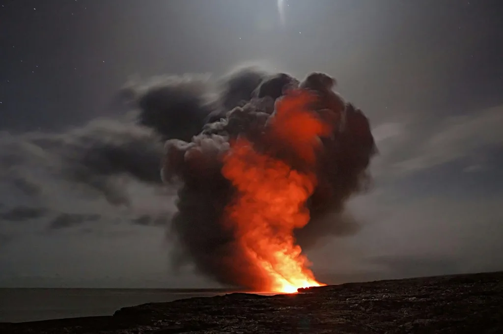 pexels-photo-417070-417070 Volcanic eruption with smoke and lava under a starry night sky.
